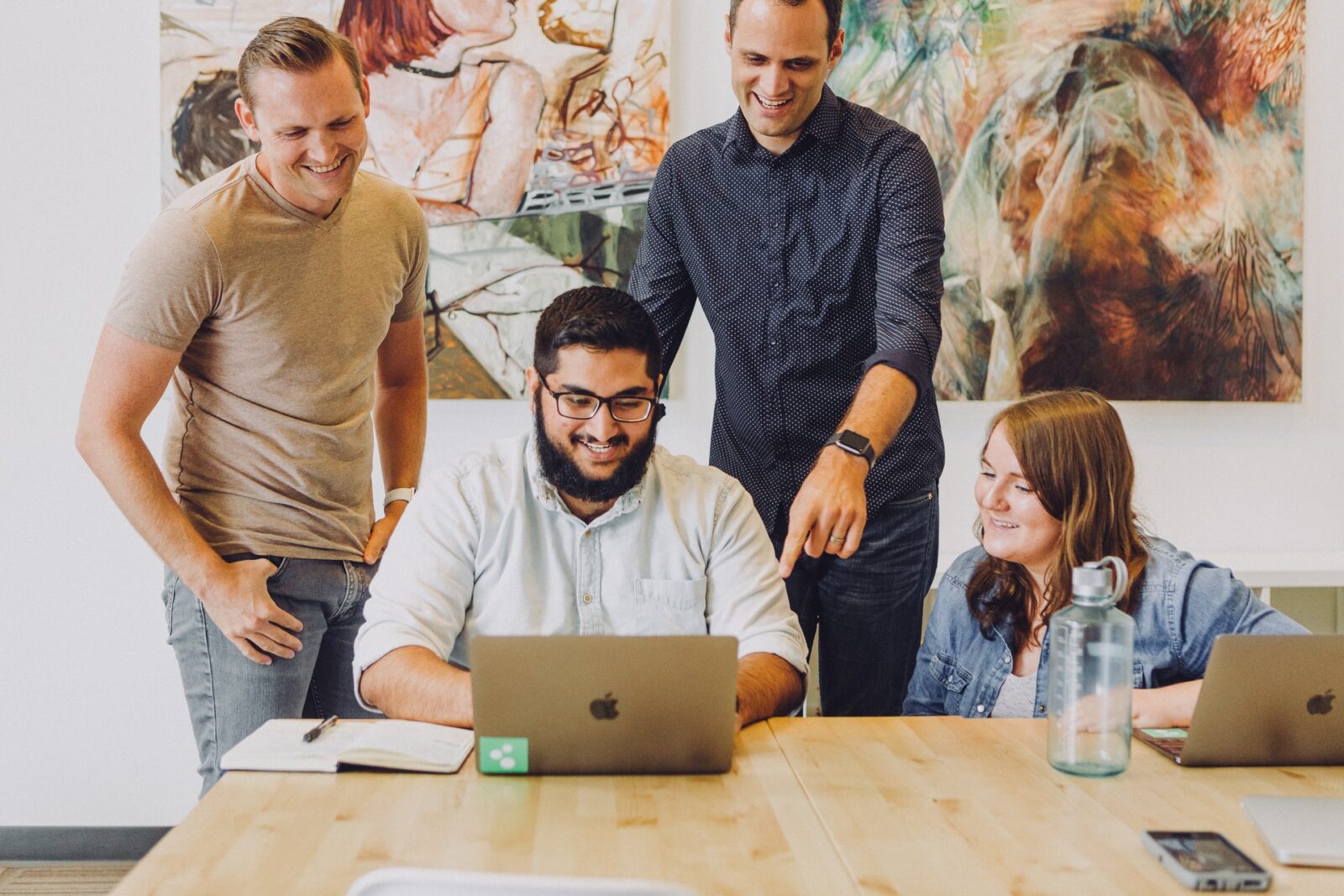 four employees smiling at a computer