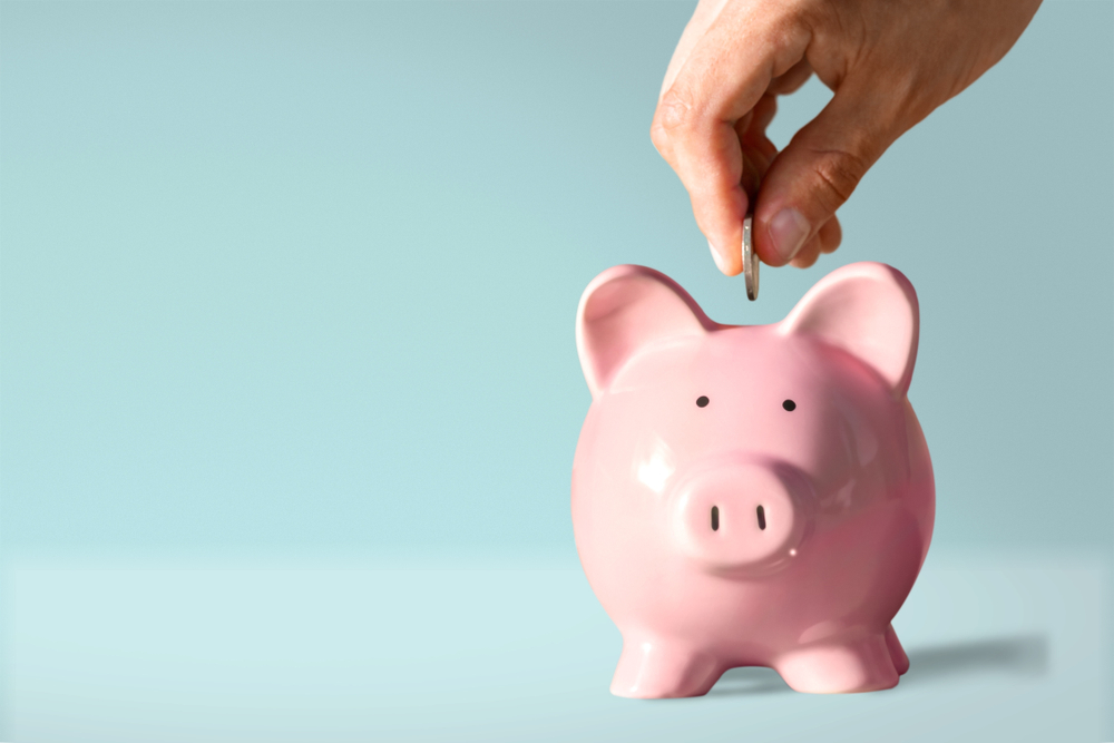 a man putting a coin in a pink piggy bank