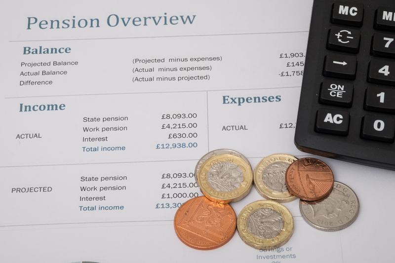 coins and a calculator laying on top of a pension overview document