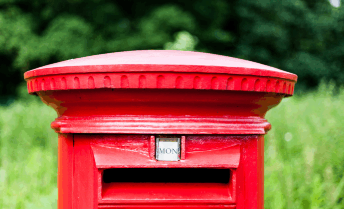 Red mail post box in grass field